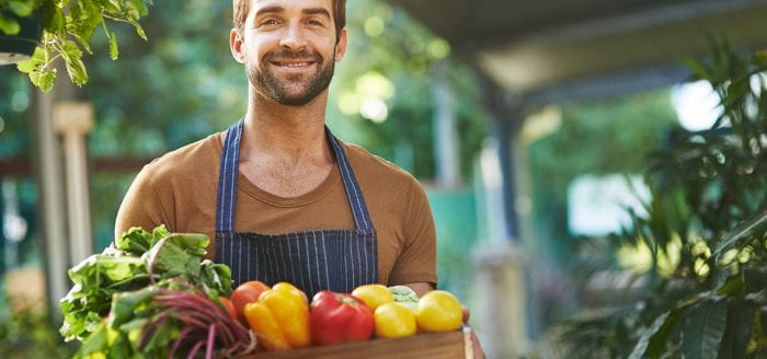 A man holds a crate full of healthy produce