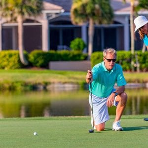 Lady and man hitting golf ball into hole